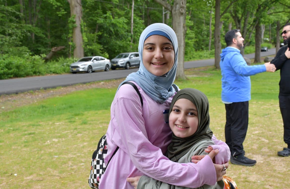Two young sisters embracing and smiling on the Eid ul Ghadir hike